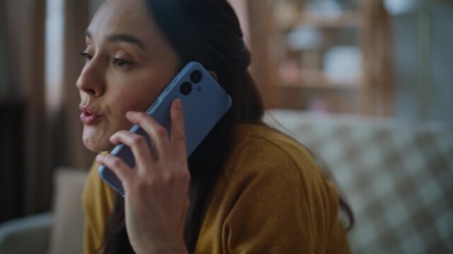 Displeased brunette talking cellphone sitting couch closeup. Woman calling