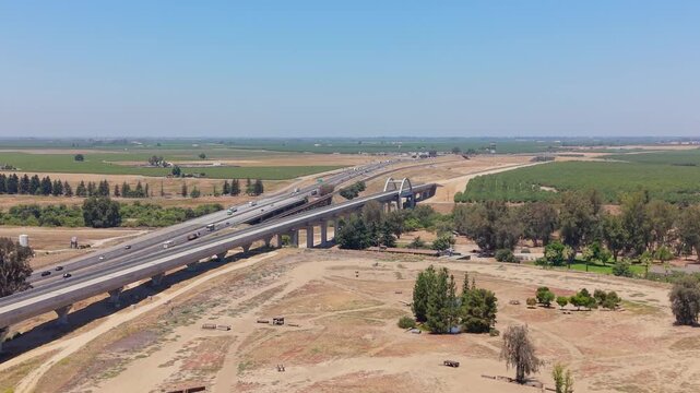 Reversing Aerial Drone Shot Over California High Speed Rail Construction With San Joaquin River Viaduct Overpass Freeway and Farmland
