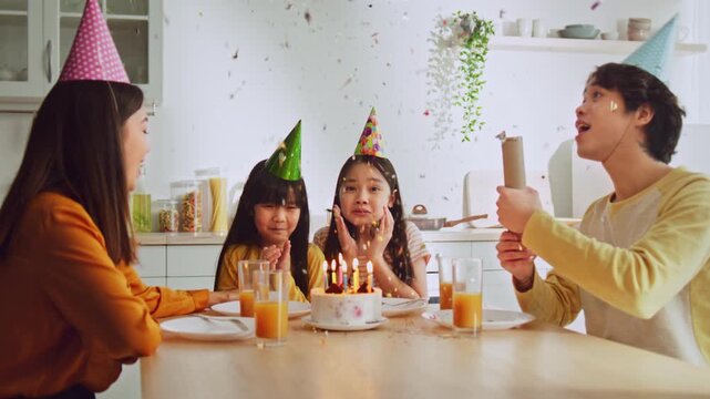 Joyful Expression. Happy Asian Girls Aged 5-10 Celebrating Birthday With Cake Surrounded By Friends At Home. Fun Birthday Party Moment In Cozy Kitchen Setting. Family Celebration.