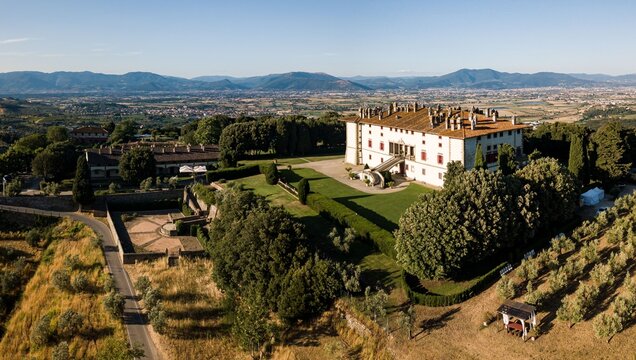 Aerial view of Villa Medicea di Artimino surrounded by lush gardens, olive groves, and rolling hills in the Tuscan countryside, Artimino, Tuscany, Italy.