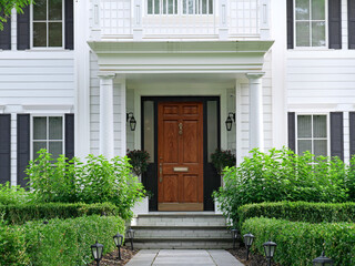 Fototapeta premium House with white siding and elegant portico entrance and wood grain front door