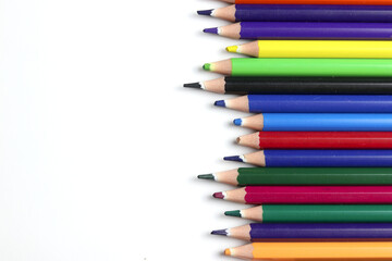 Fototapeta premium A row of sharpened colored pencils arranged on a white background with ample copy space, symbolizing creativity, education, art, drawing, and school supplies.