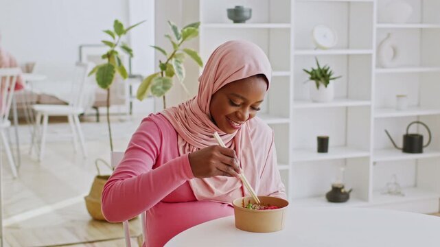 Happy Pregnant Black Woman Smiling While Eating Healthy Salad From Bowl At Home Kitchen, Embracing Healthy Eating Habits During Pregnancy, Focusing On Nutrition And Wellness. Weight Loss Concept.