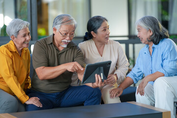 Fototapeta premium Group of happy elderly Asian friends smiling during a group activity in a bright senior living lounge, portraying joyful community, active retirement and social wellbeing in elderly (0936)