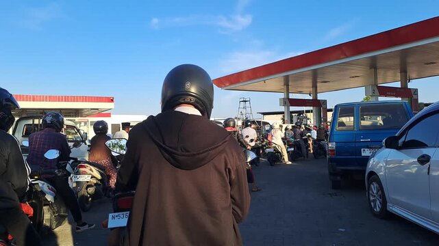 Long queue of motorcycles and cars at gas station during fuel shortage. Traffic jam spilling onto street. Crowd waiting for fuel. Editorial stock video 4K for news, crisis, shortage, energy, transport