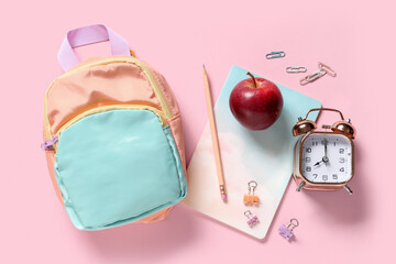 Obraz premium Tasty apple, alarm clock, backpack and different school stationery on pink background