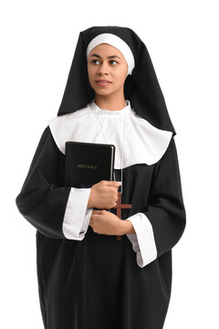 Portrait of young nun with Bible on white background