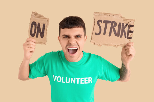 Protesting volunteer holding placard with text ON STRIKE against beige background