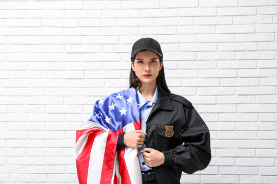 Female police officer with USA flag on white brick background
