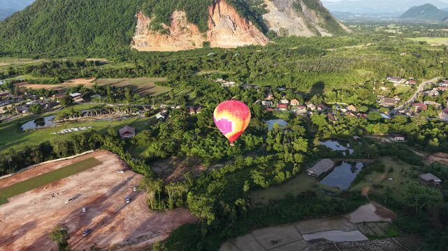 Vang Vieng , Laos - 07/02/2025:Aerial drone footage of colorful hot air balloons flying above the scenic landscape of Vang Vieng in Laos during sunrise
