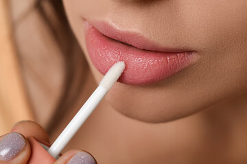 Naklejka premium Young woman applying lipgloss, closeup