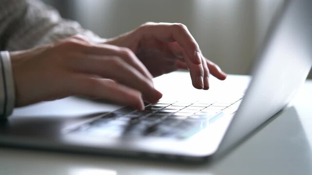 Hands type on a laptop keyboard. Fingers move quickly over the keys. Focused work or study session. Soft lighting adds calm atmosphere. Common scene for remote work or online learning