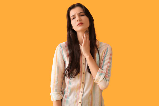 Young woman with thyroid gland problem on yellow background