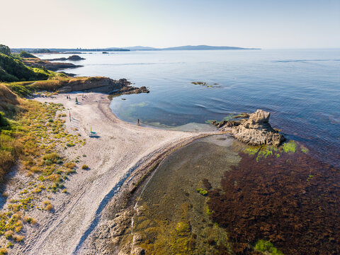 Aerial view of the clam beach with sandy shores, rocky formations, and clear coastal waters along the Black Sea coastline in Lozenets, Tsarevo, Bulgaria.