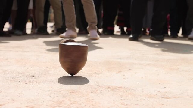 Close-up footage of a traditional Hmong wooden spinning top used in the cultural game known locally as "Dao Tawl Lu" during a hill tribe festival in Northern Thailand. The spinning top stands in sharp