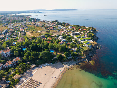 Aerial view of Oasis Beach with rows of sun loungers, surrounded by lush greenery and residential villas along the coastline in Lozenets, Burgas, Bulgaria.
