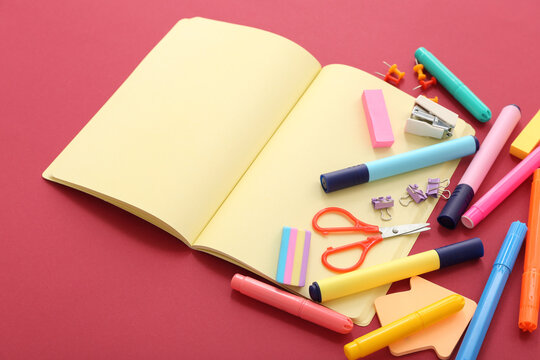 Composition with blank open notebook and school supplies on color background