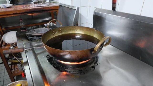 Cooking Oil Heating in a Brass Wok on Commercial Gas Stove