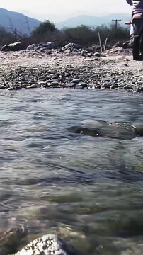 Close Up Of Motorcycle Wheels Crossing Water Stream Outdoors - 4K Vertical
