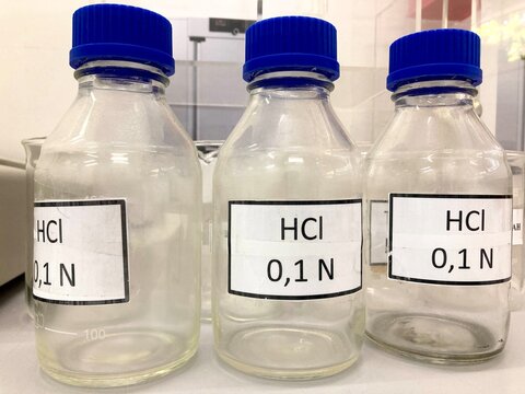 laboratory bottles of hcl solution with blue caps on a table