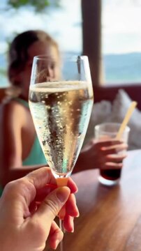  Toasting with Champagne Flute Glass at Restaurant Table with Little Girl in Background