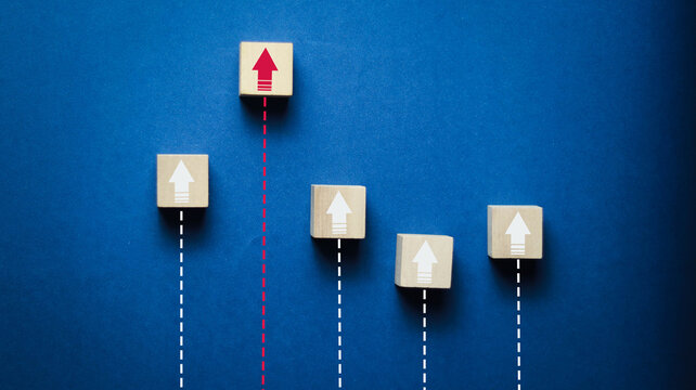 Wooden blocks with upward arrows on a blue background symbolize business growth, leadership, success, performance improvement, goal achievement, strategy, innovation, and competitive advantage with co