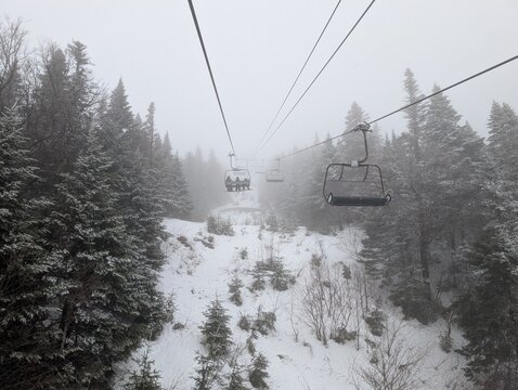 Skiing in winter - chairlift gondola and ski slopes for skiing and snowboarding  between trees on frosty day with beautiful views in  mountains