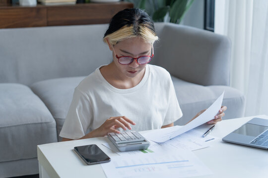Asian woman using calculator calculating Monthly expenses and Working With Laptop at home