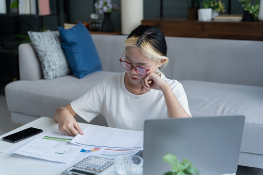 Asian woman using calculator calculating Monthly expenses and Working With Laptop at home