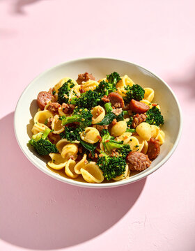 Plated orecchiette pasta with glossy broccoli rabe and sausage 