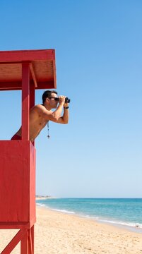 Lifeguard on duty looking at ocean from wooden watchtower