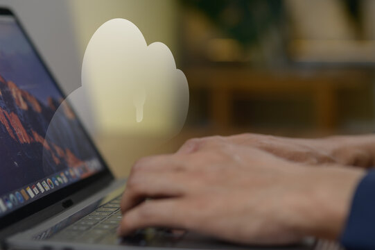 Person typing on laptop keyboard with cloud icon projection in background