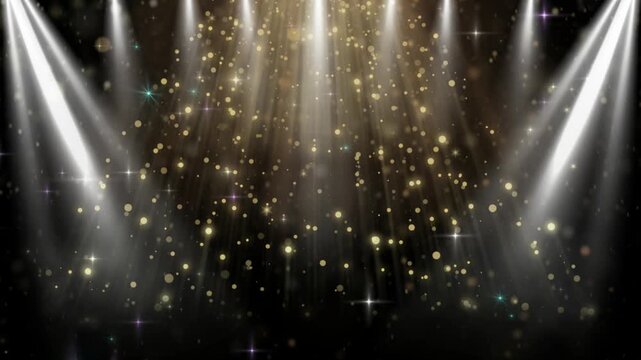 Spotlights shine down on a dark stage creating a dramatic atmosphere filled with golden floating dust.