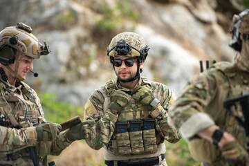 Fototapeta premium Military personnel discuss equipment and mission details during a tactical field briefing
