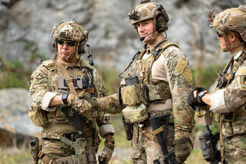 Fototapeta premium Military personnel communicate and coordinate during a field operation briefing