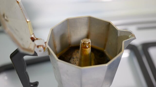 Coffee brewing process in italian moka pot. Traditional italian moka pot brewing fresh, hot espresso on a gas stove, with the dark beverage slowly rising and filling the upper chamber