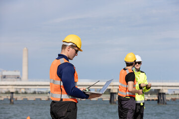 Fototapeta premium Engineers collaborating at an oil and gas refinery site with industrial infrastructure in the background