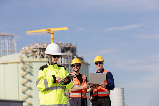 Engineers collaborating at an oil and gas refinery professionals in safety gear inspecting operations with technology