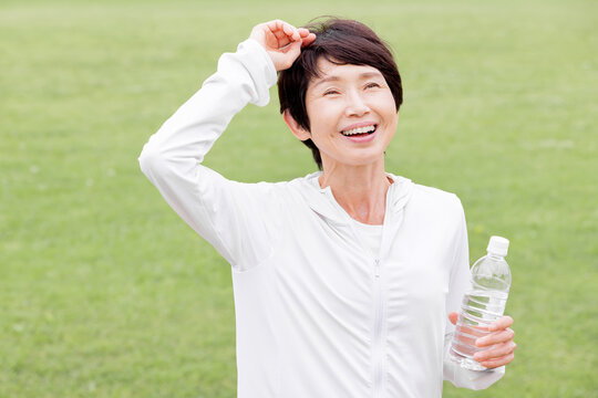 運動後に水分補給をしながら笑顔を見せるアクティブシニア女性