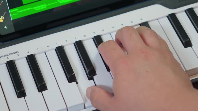 Close up of musician hand playing a song on white MIDI keyboard controller