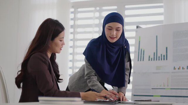 Two business colleagues multiethnic working in office, asian muslim