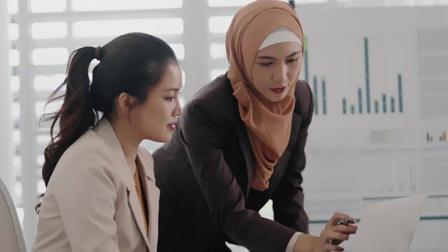 Two business colleagues multiethnic working in office, asian muslim