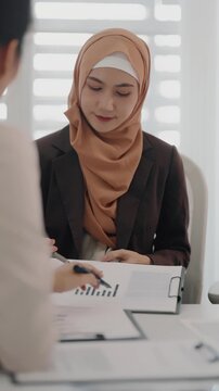 Two business colleagues multiethnic working in office, asian muslim