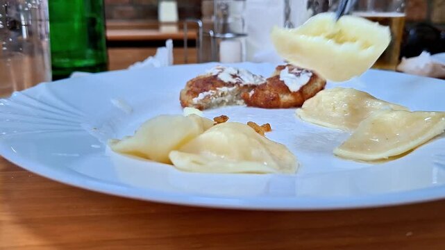 Homemade dumplings paired with crispy potato pancakes, beautifully served on a clean white plate. A comforting traditional meal showcasing rustic flavors, fresh ingredients, and inviting presentation