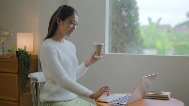 Woman works remotely from living room using laptop comfortably