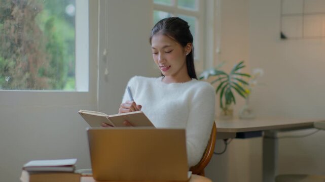 woman writing diary planning on notebook at home
