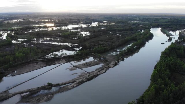 Aerial view of tropical river delta at sunset. Sunlight reflects in calm waters of river. Green forest and trees surround the watercourse at beautiful evening.