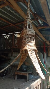 Kap lampu gantung tradisional dari anyaman bambu dan serat alami bergaya etnik untuk dekorasi interior ruangan, diambil dari sudut pandang rendah