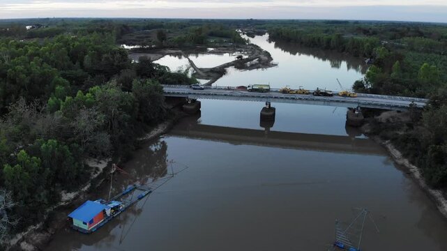 Aerial view of tropical river delta at sunset. Sunlight reflects in calm waters of river. Green forest and trees surround the watercourse at beautiful evening.