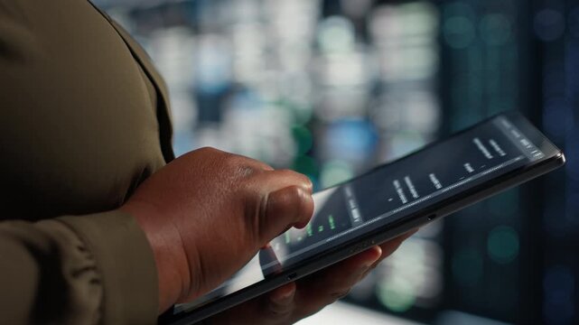 Programmer uses a tablet device in a server farm for workload capacity upgrades, supporting equipment monitoring, system reliability and server infrastructure management.